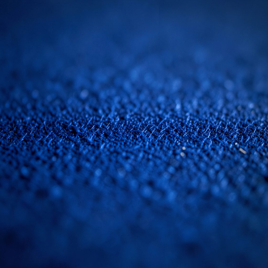 Extreme close-up of woven kite canopy fabric in bright yellow and blue, showing ripstop texture and taut stitched seams, energetic and sporty mood